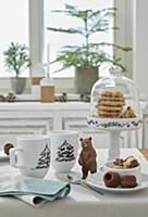 Mugs painted with fir trees on set table