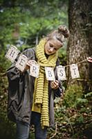 Girl hanging up autumn garland in woods