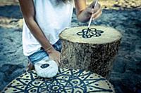 Painting a black mandala on a tree stump