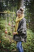 Girl hanging up handmade bird feeders in woods