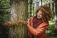 Woman in woods tying garland of rose hips around t