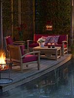 Lounge furniture on candlelit terrace next to pool