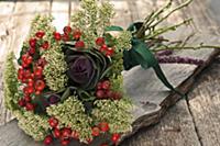 Autumnal flower arrangement with rose hips on wood