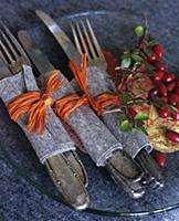 Silver cutlery wrapped in felt and raffia on glass