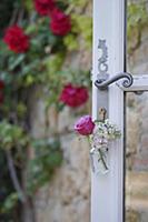 Rose and lilac in small glass bottles hung from do