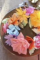 Wreath of colourful paper flowers on plate in suns