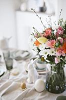 Vase of colourful flowers on Easter breakfast tabl