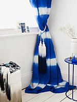 Blue and white curtain with tassels in corner of r