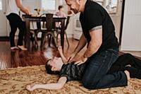 Father and son wrestling on carpet at home