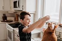 Boy playing with cat on kitchen worktop
