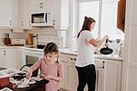 Girl arranging cards in kitchen, mother pouring ho