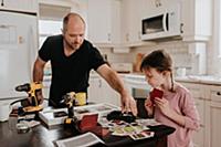 Girl helping father arrange cards into box in kitc