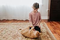 Girl playing with cat on carpet at home