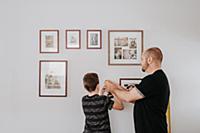 Father teaching son drill wall for picture frames