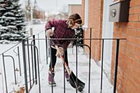 Girl shovelling snow on porch