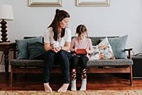 Mother watching daughter play on couch