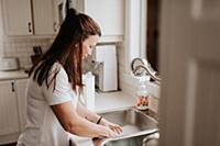 Woman washing up in kitchen sink