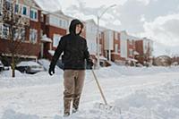 Man clearing snow-covered road with shovel, Toront