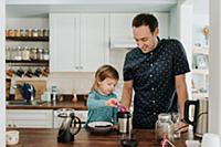 Female toddler and father preparing food at kitche