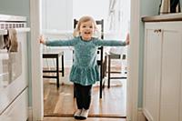 Female toddler standing in kitchen doorway, portra