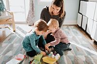 Female toddler playing with mother and baby brothe