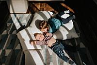 Baby boy and toddler sister lying on cushions on l