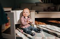Baby boy sitting playing on living room rug