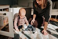 Mother playing with baby son on living room rug
