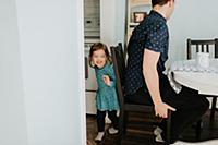 Female toddler hiding from father at table