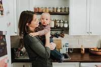 Mother carrying baby son in kitchen