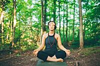 Woman doing enlightened pose in forest