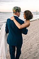 Romantic groom carrying bride on lakeside, rear vi