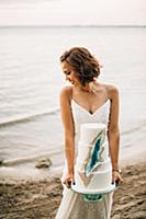Young bride carrying wedding cake on lakeside,  La