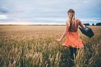 Woman swinging suitcase in wheat field, Edmonton, 
