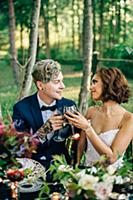 Bride and groom raising a glass at forest table
