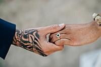 Bride and tattooed groom holding hands, cropped