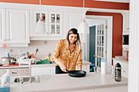 Mid adult woman with frying pan at kitchen counter