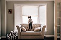 Girl standing on sofa looking through living room 