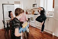 Boy shooting father with foam ball gun in kitchen