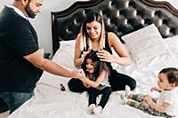 Baby boy sitting on bed while mother and father pl