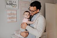 Father with baby daughter in baby's room