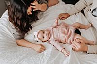 Couple with baby daughter on bed in bedroom