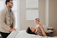 Couple with baby daughter on bed in bedroom