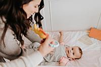 Mother putting baby daughter to bed in crib