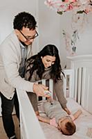 Couple putting baby daughter to bed in crib