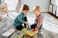Female toddler playing with baby brother in living