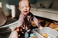 Baby boy sitting on living room floor playing with