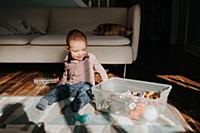 Baby boy sitting on living room floor playing with