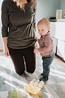 Mother kneeling in living room with baby son
