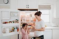 Mother giving daughter cold meat from fridge